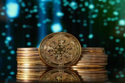 Golden Cardano ADA coin stacked with other coins against blue digital background